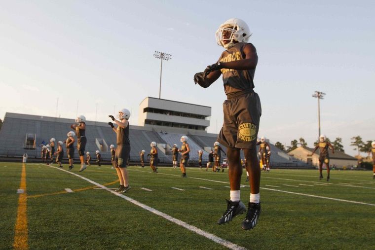 Conroe football players warm up as the sun goes down Thursday at Buddy Moorhead Memorial Stadium.